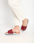 Minimalist men’s maroon sliders with adjustable Velcro fit paired with white trousers