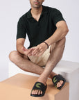 Indoor shot of a man wearing Dot Fusion sliders. Paired with beige shorts and black polo T-shirt