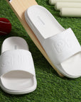 White sliders for men with cushioned AirSoft Sole on a green background