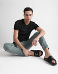 A young man pairs black men’s sliders with cargo pants and a black T-shirt, blending bold monochrome style with everyday casual comfort.