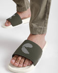 Close-up of white and olive men’s sliders worn with cargo pants, highlighting the textured strap and contoured footbed design.