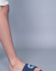Young men in casual settings wear navy blue men’s sliders with shorts and tattered denims, highlighting versatile styling and comfort across various Chupps slider designs.