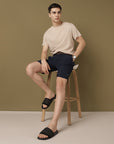 model picture of rover wearing beige T-shirt and blue shorts with black flip-flops