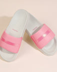 Pink and clear slide sandals on a beige background