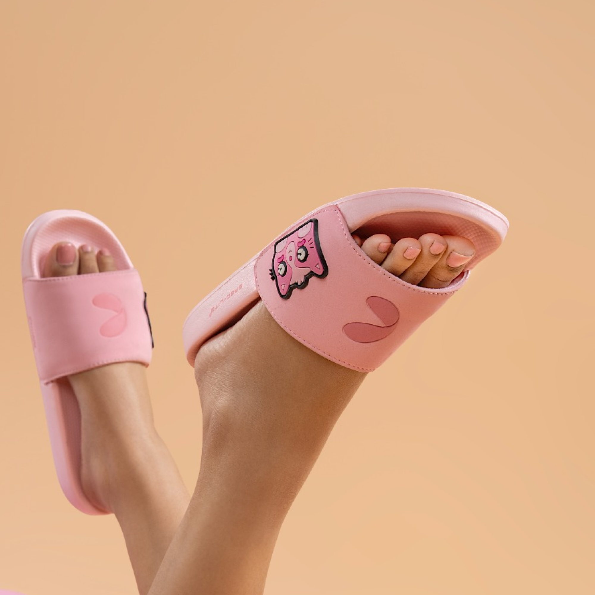 Person wearing pink Chupps slippers with a cartoon design on a beige background.